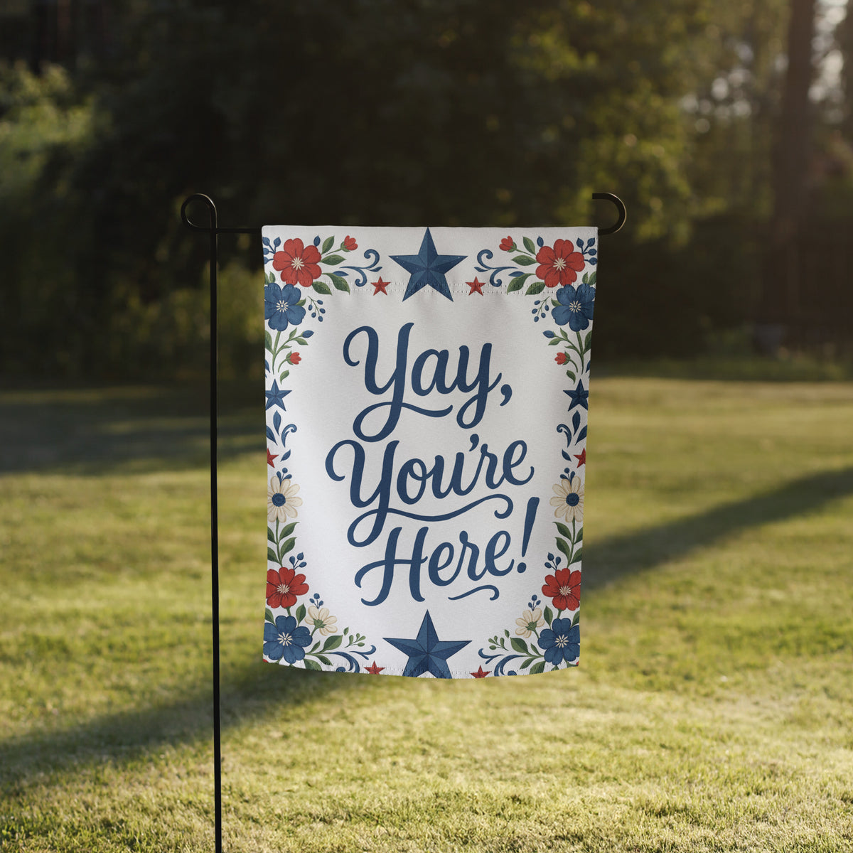 Red, white, and blue floral garden flag with folk-inspired stars and the phrase Yay, You’re Here in navy script.